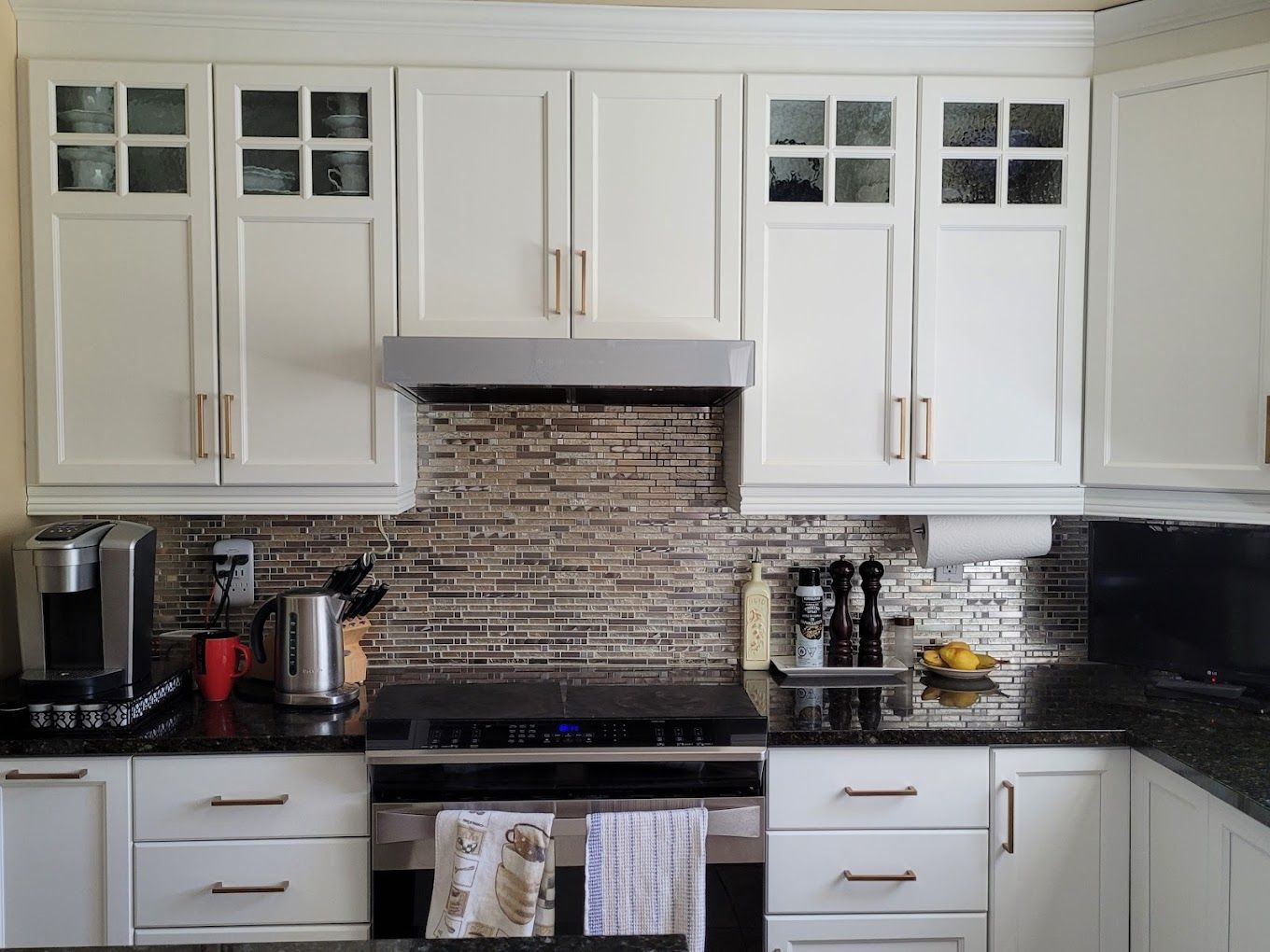 Une cuisine avec des armoires blanches et des comptoirs noirs