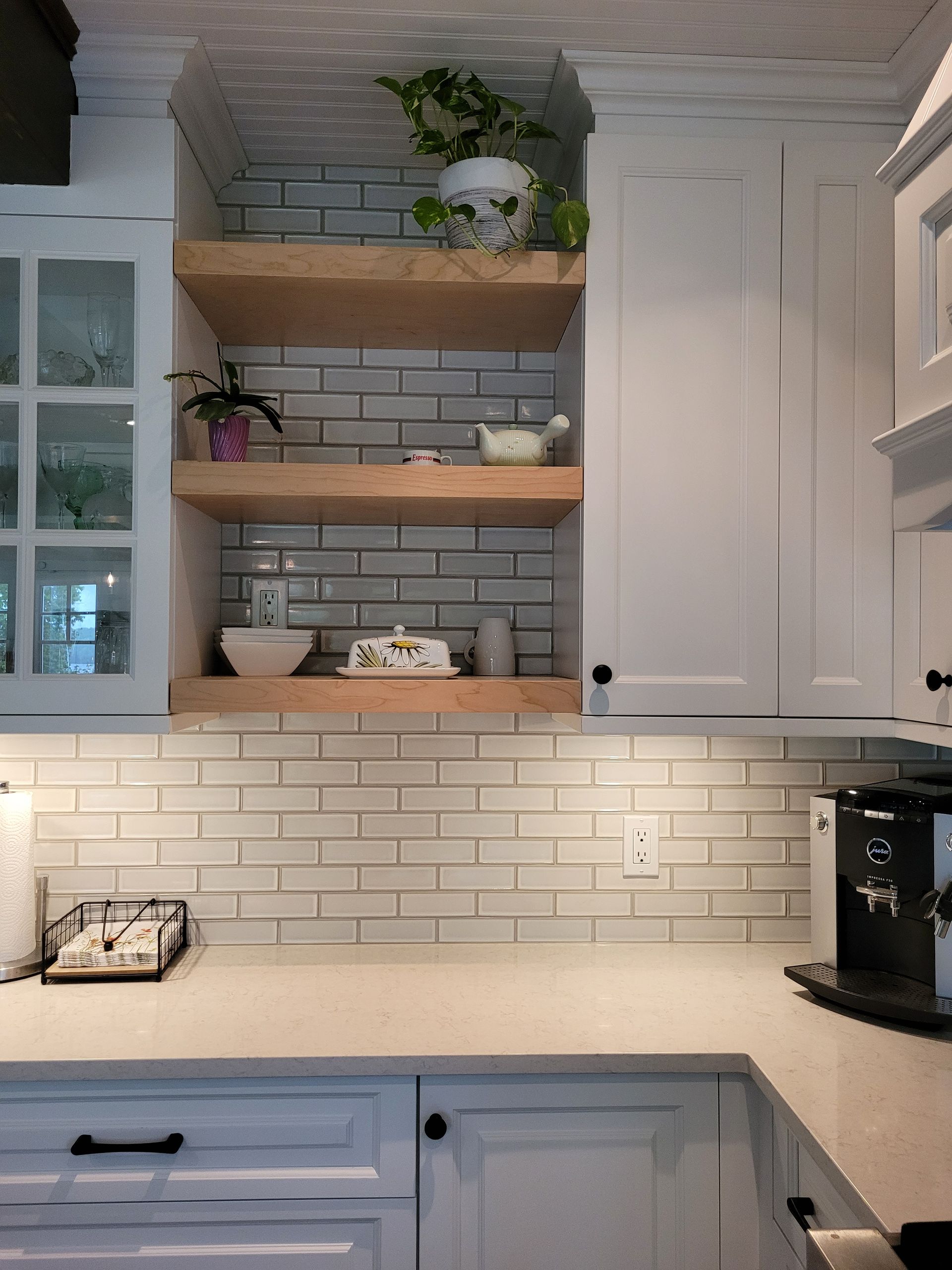 Une cuisine avec des armoires blanches et un mur de briques.