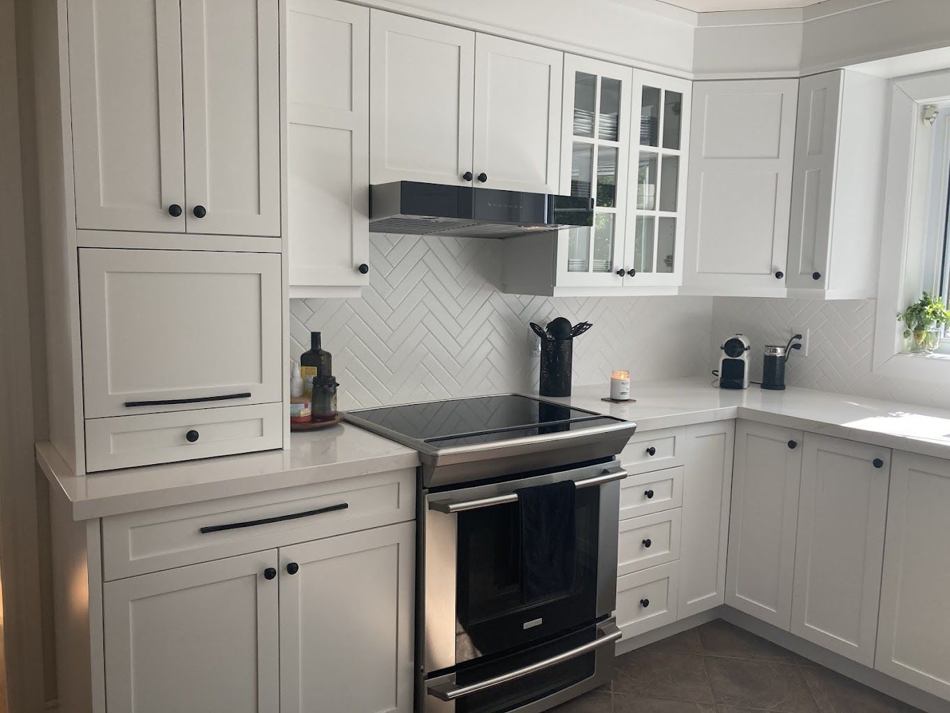 Une cuisine avec armoires blanches et appareils électroménagers en acier inoxydable.