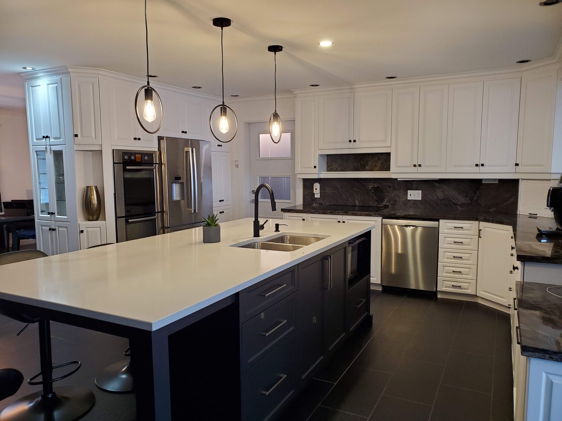 Une cuisine avec un grand îlot au milieu et des électroménagers en acier inoxydable.