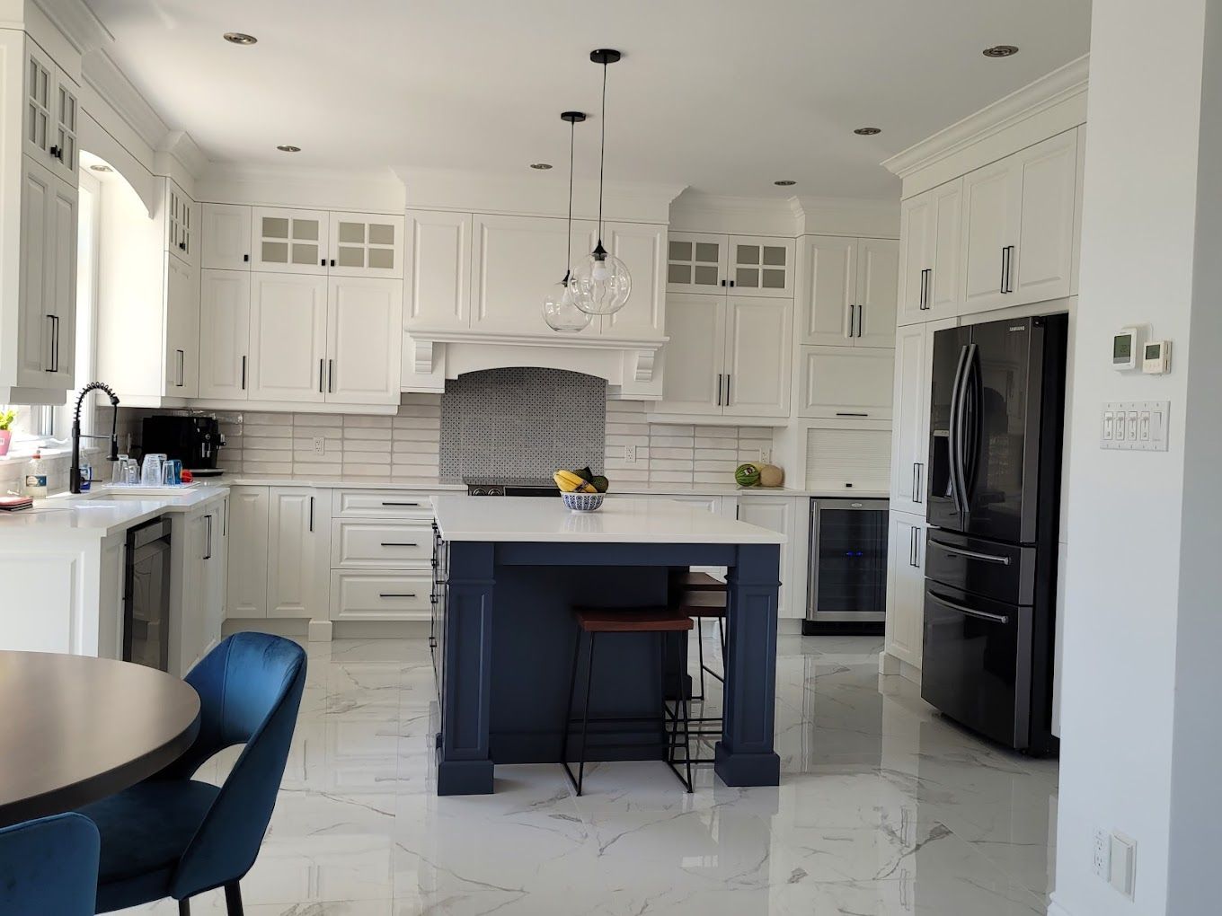 Une cuisine avec des armoires blanches et un îlot bleu.