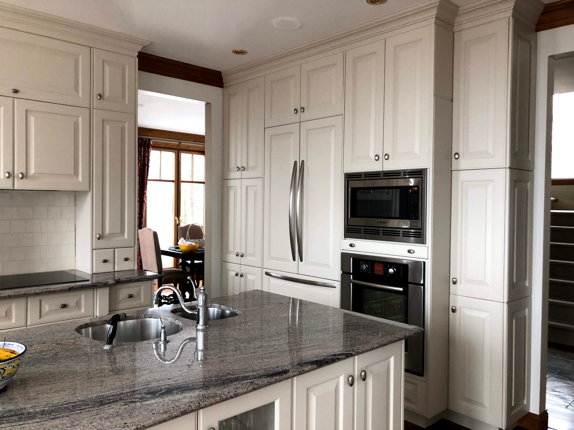 Une cuisine avec armoires blanches et comptoirs en granit