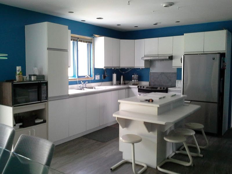 Une cuisine avec des armoires blanches et des murs bleus