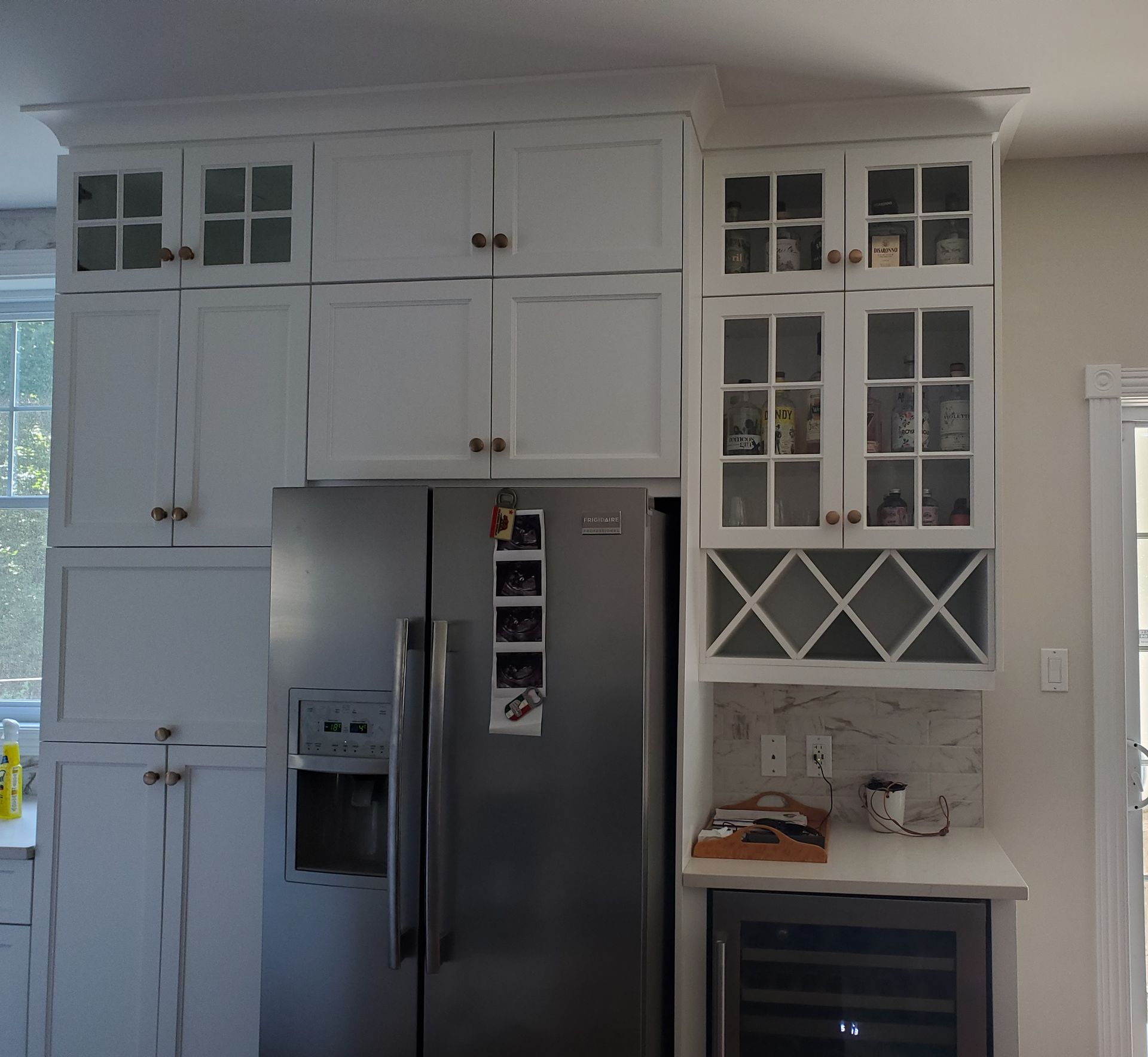 Une cuisine avec des armoires blanches et un réfrigérateur en acier inoxydable