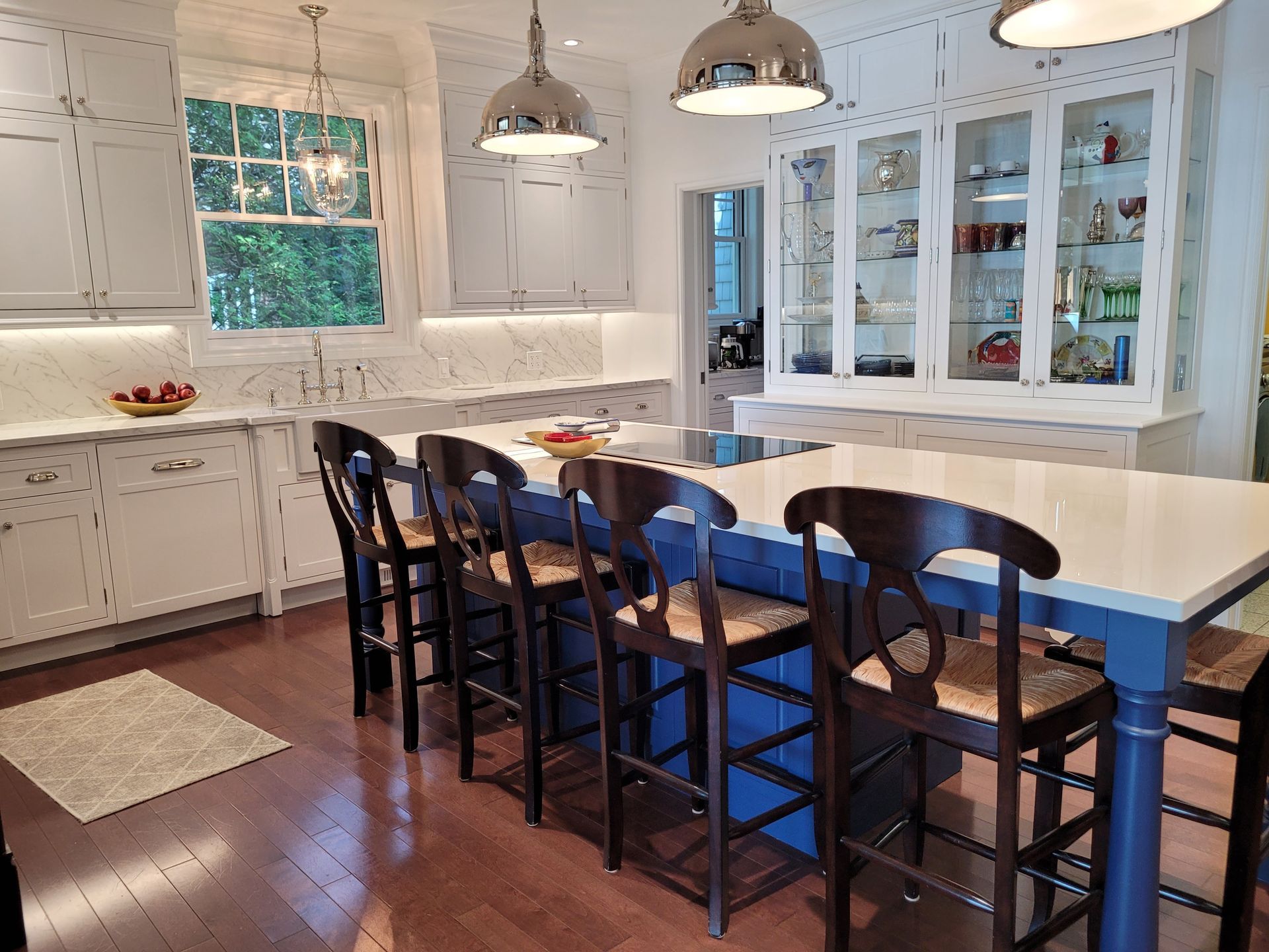 Une cuisine avec armoires blanches et un îlot bleu avec tabourets.