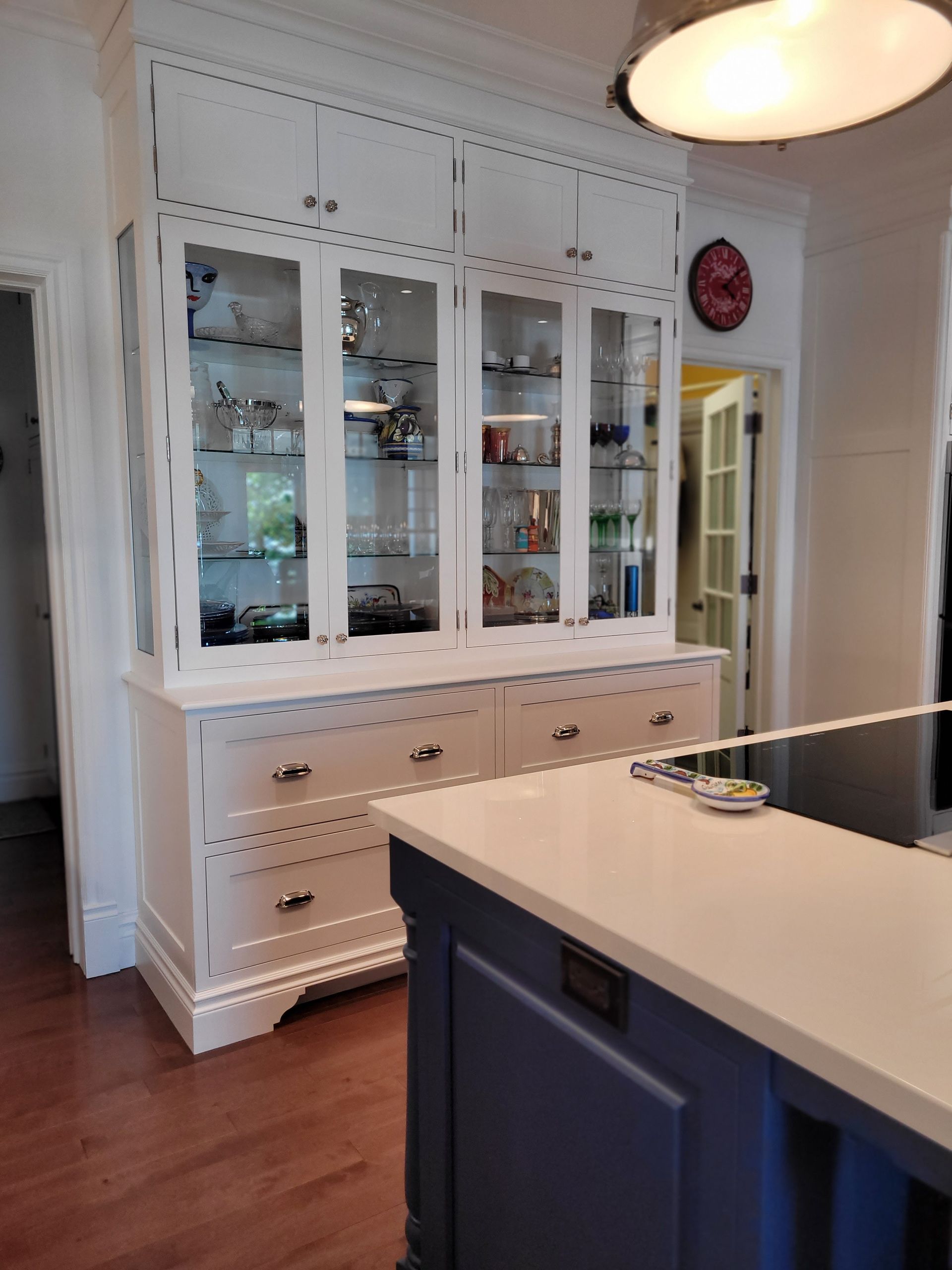 Une cuisine avec un îlot bleu et des armoires blanches avec portes vitrées.