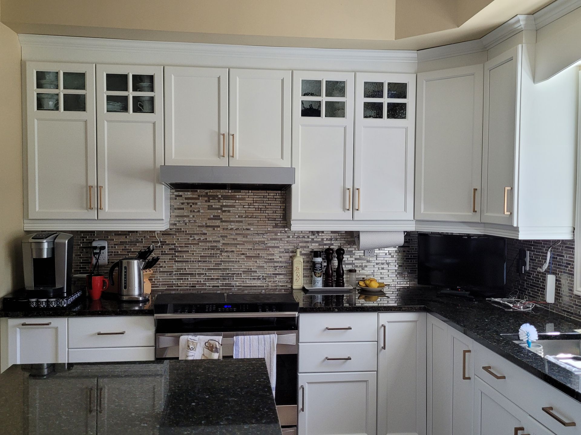 Une cuisine avec des armoires blanches et des comptoirs noirs