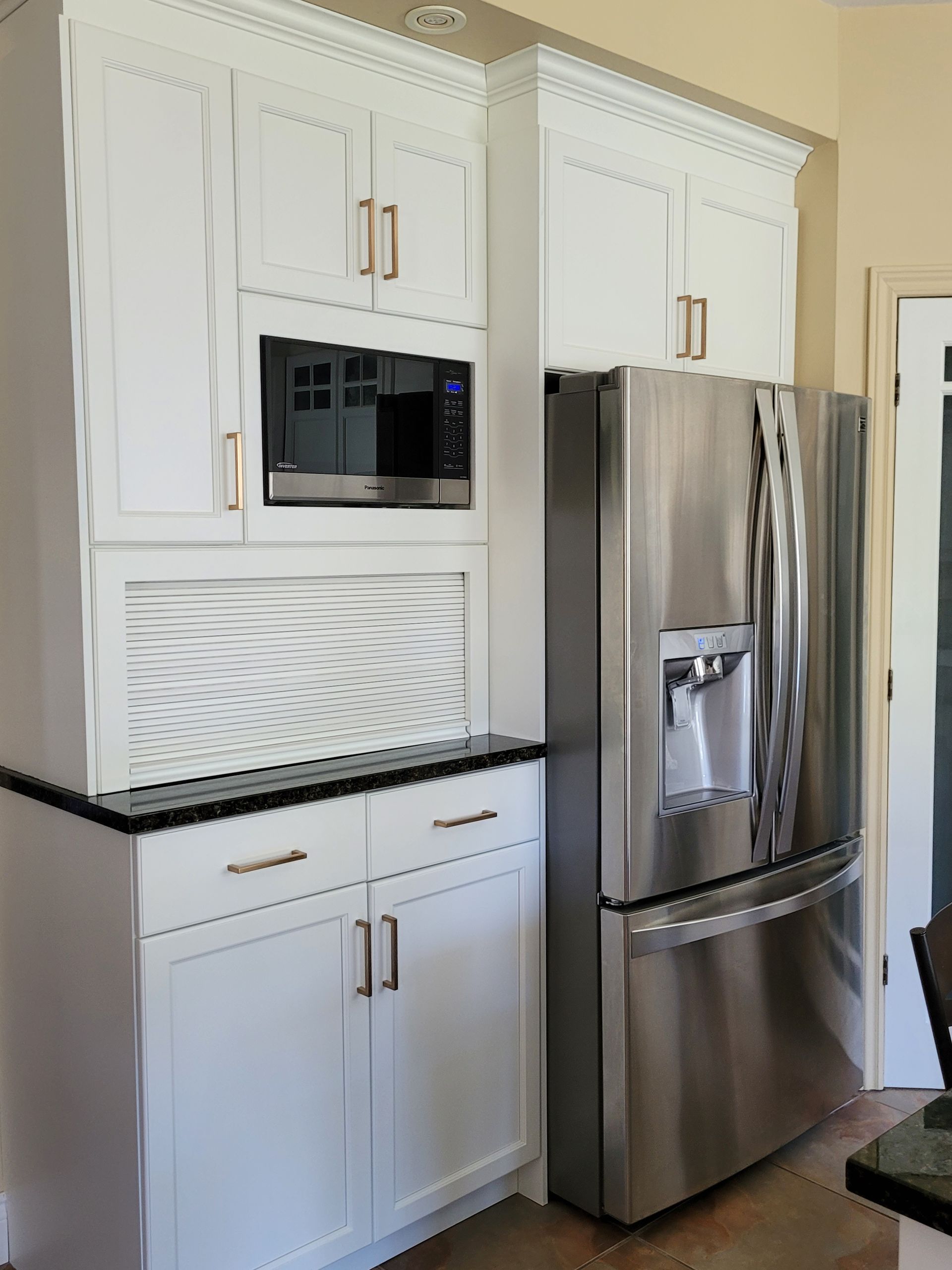 Une cuisine avec des appareils électroménagers en acier inoxydable et des armoires blanches