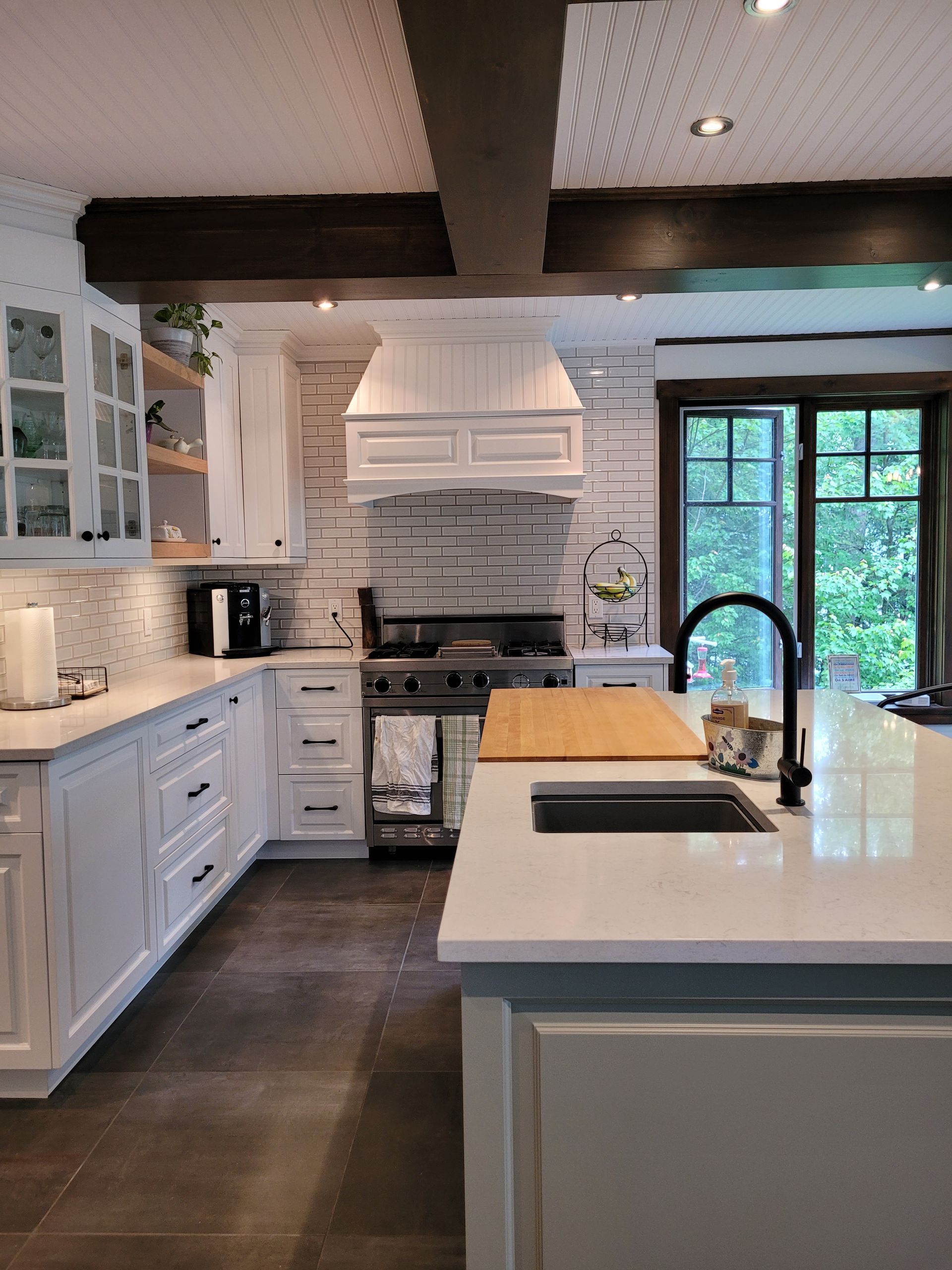 Une cuisine avec des armoires blanches, un évier et une cuisinière.