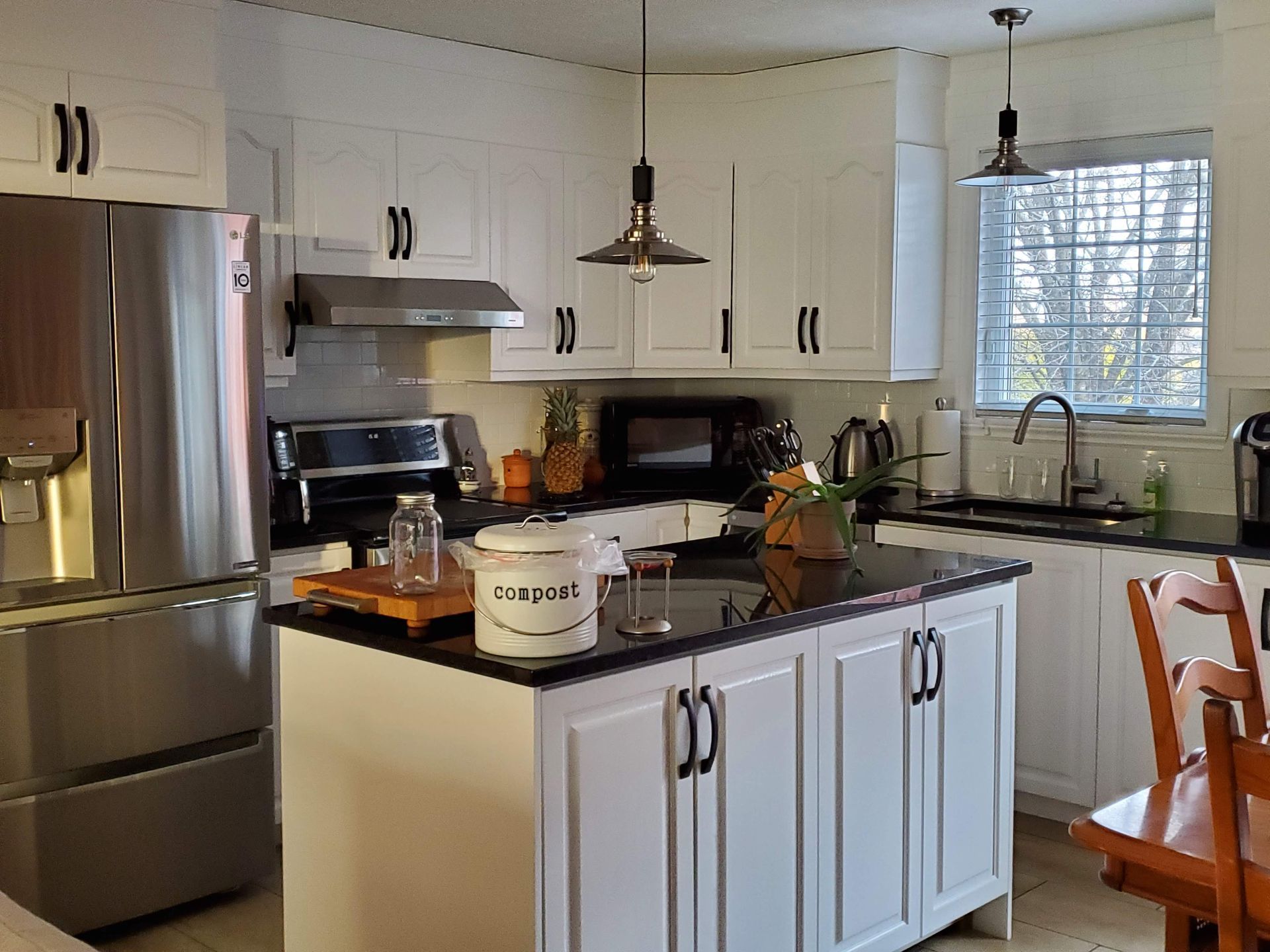 Une cuisine avec armoires blanches, appareils électroménagers en acier inoxydable et un grand îlot.