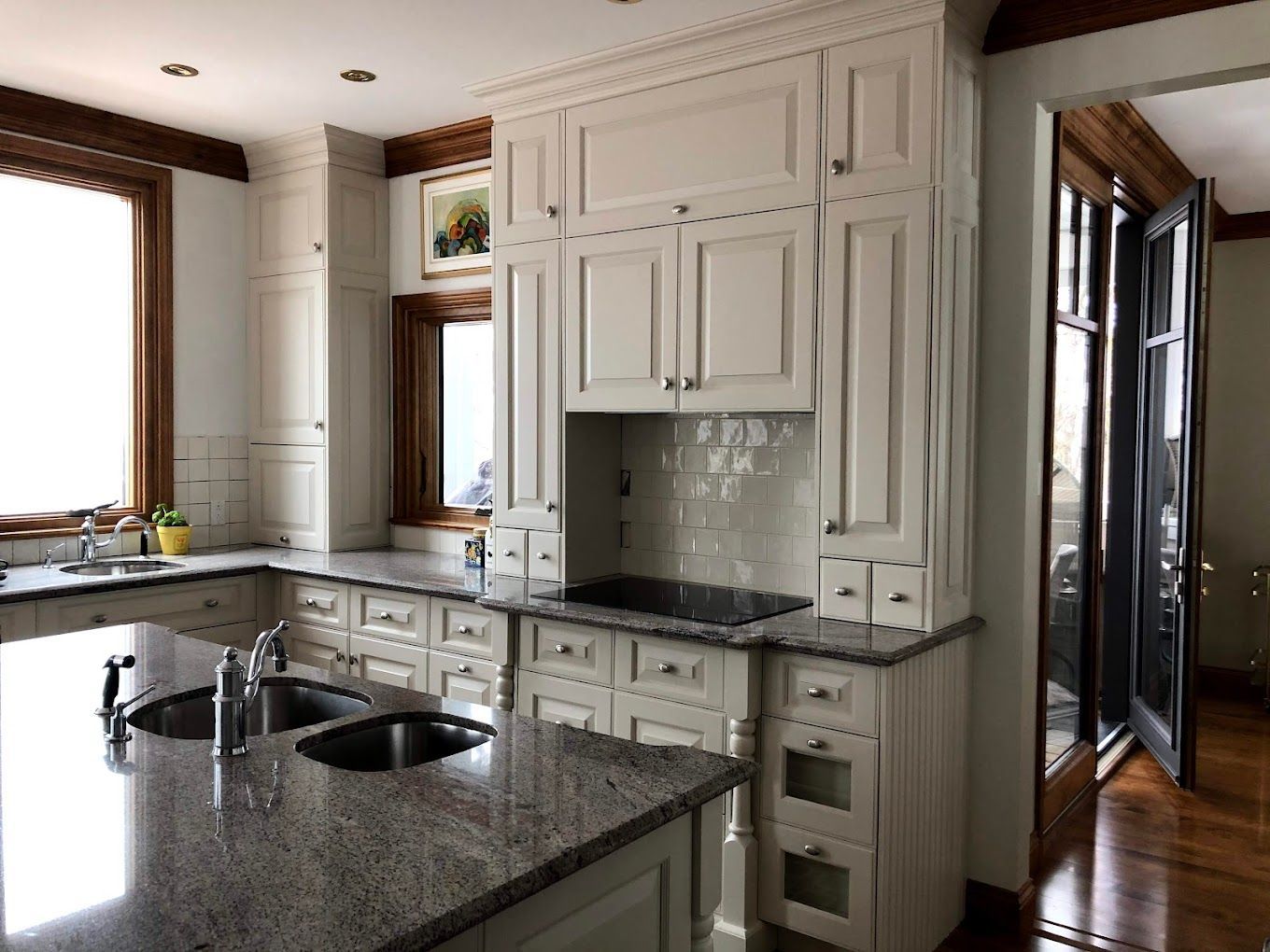 Une cuisine avec armoires blanches et comptoirs en granit.