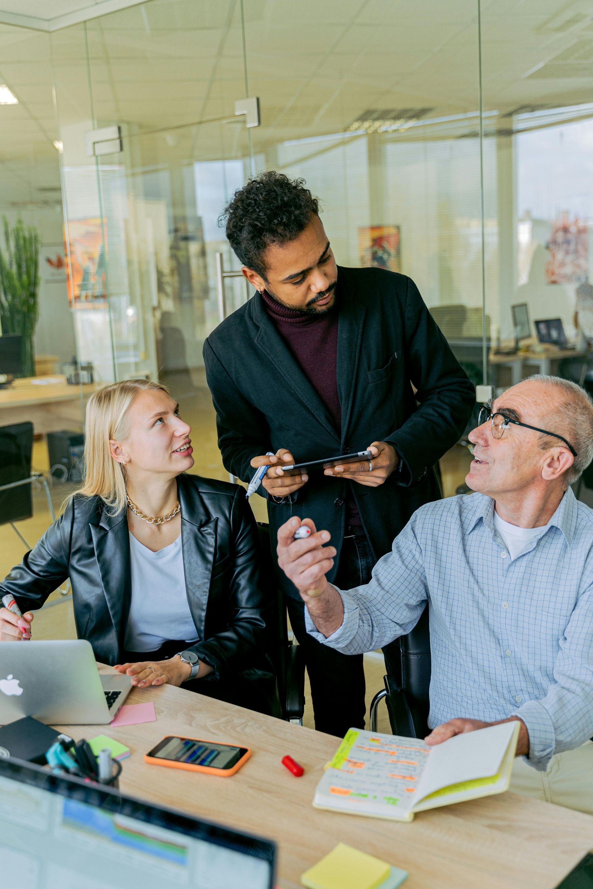 A group of people are sitting at a table in an office having a meeting.