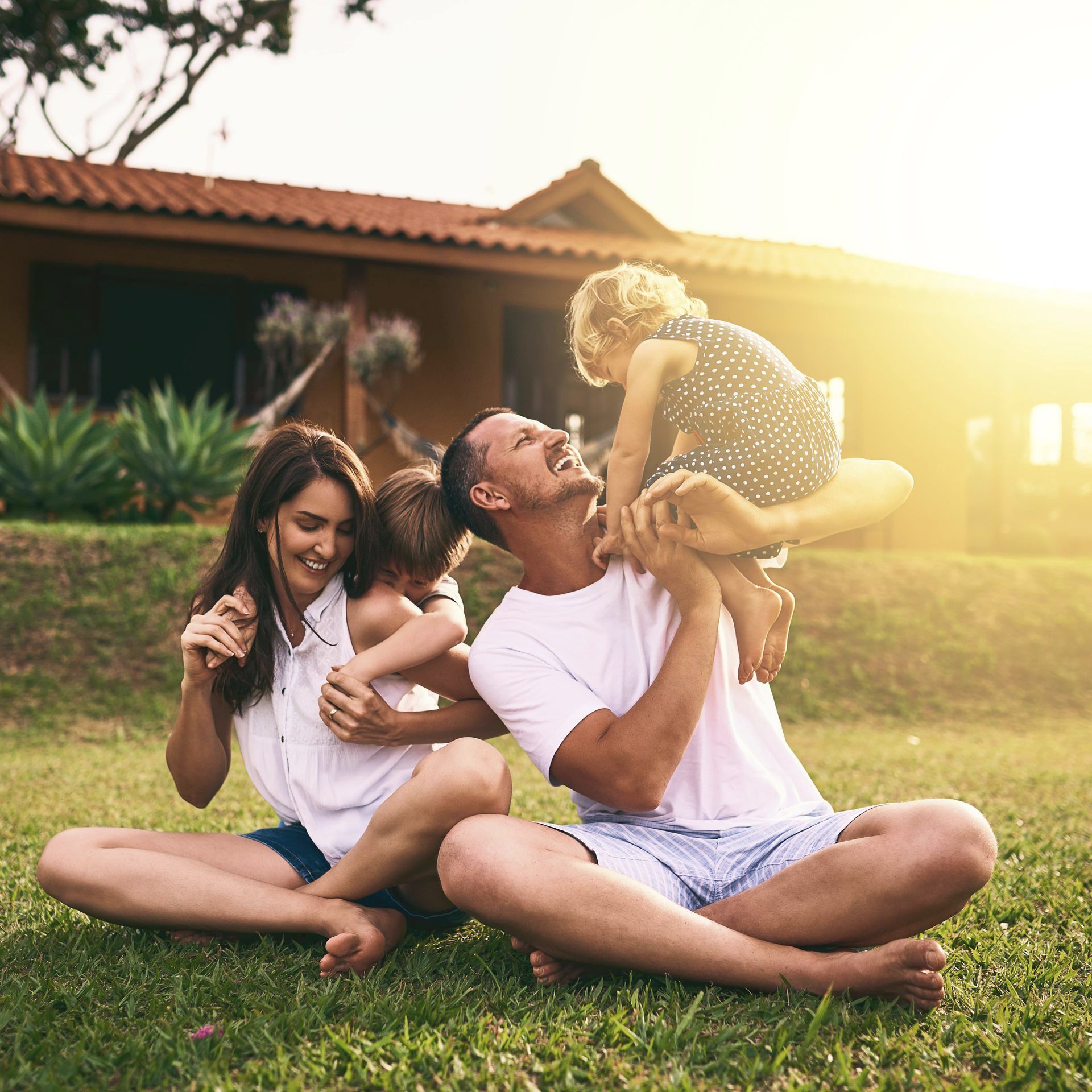 A large white house with a happy family in front of it.