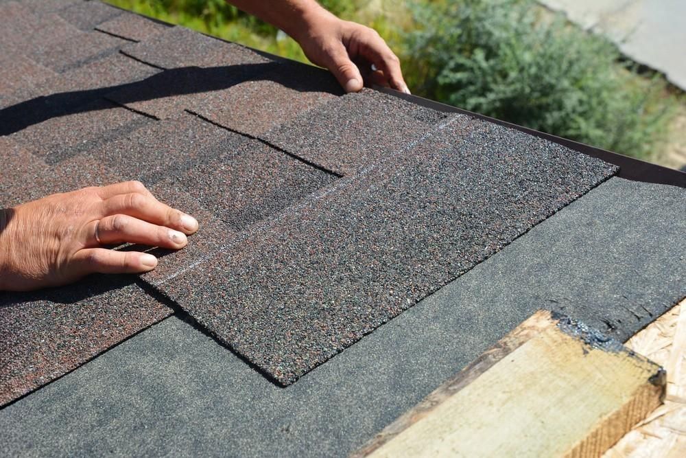 a person is laying shingles on a roof .