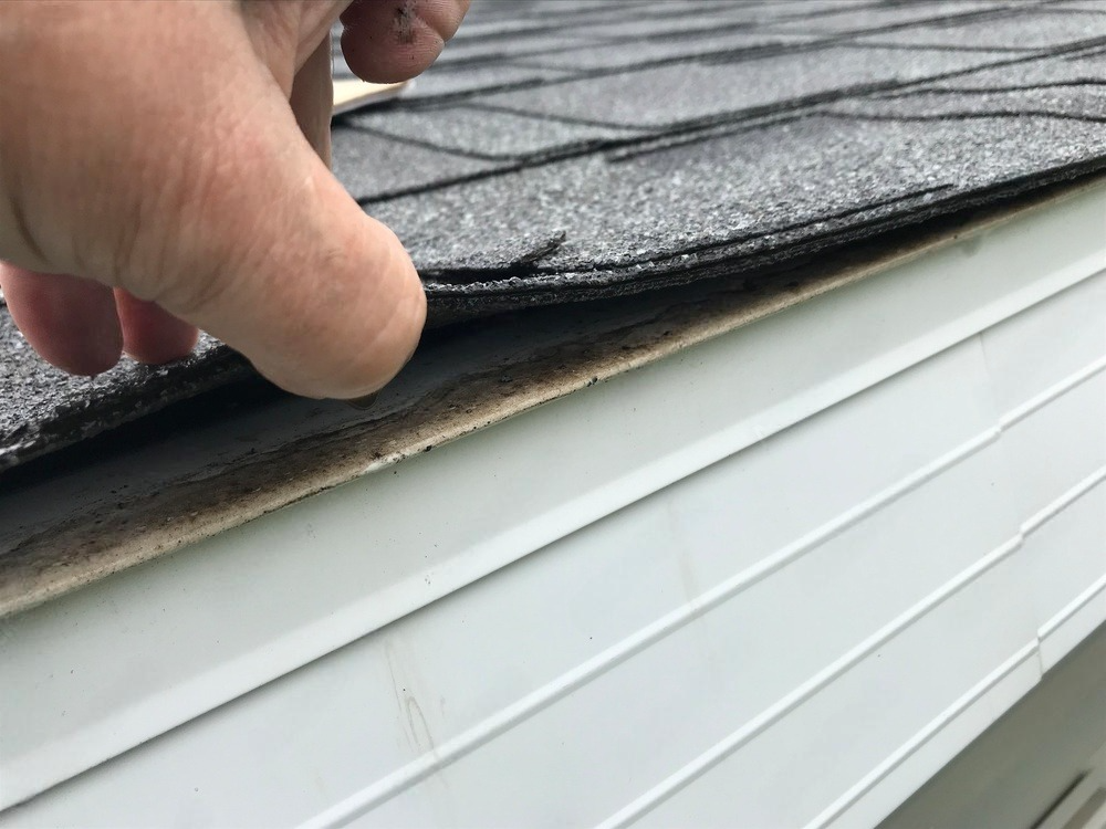 a person is holding a piece of shingles on the side of a house .