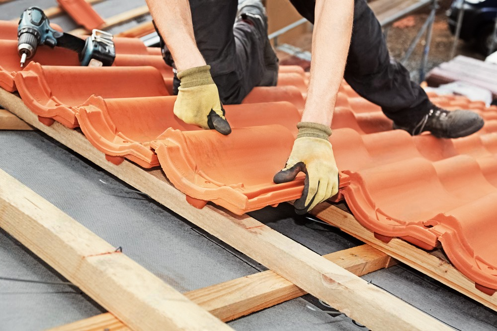 a man is installing tiles on a roof with a drill .