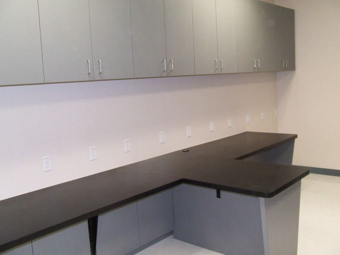 A kitchen with white cabinets and stainless steel appliances and a large island in the middle.
