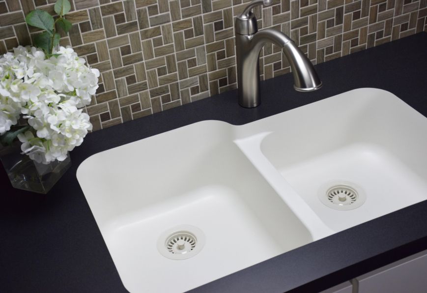 A kitchen sink with a vase of flowers next to it