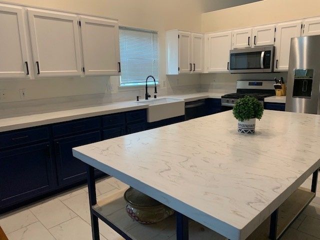 A kitchen with white cabinets and a marble counter top.