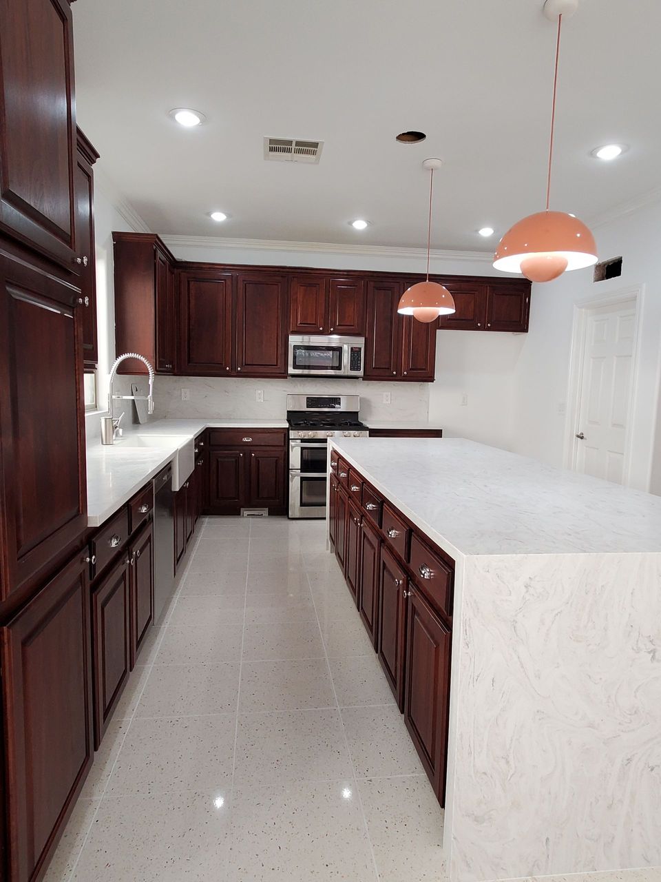 A kitchen with a sink, faucet, and marble counter tops.
