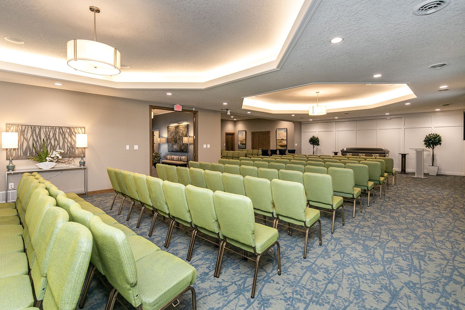 A large room with rows of green chairs and a ceiling light.