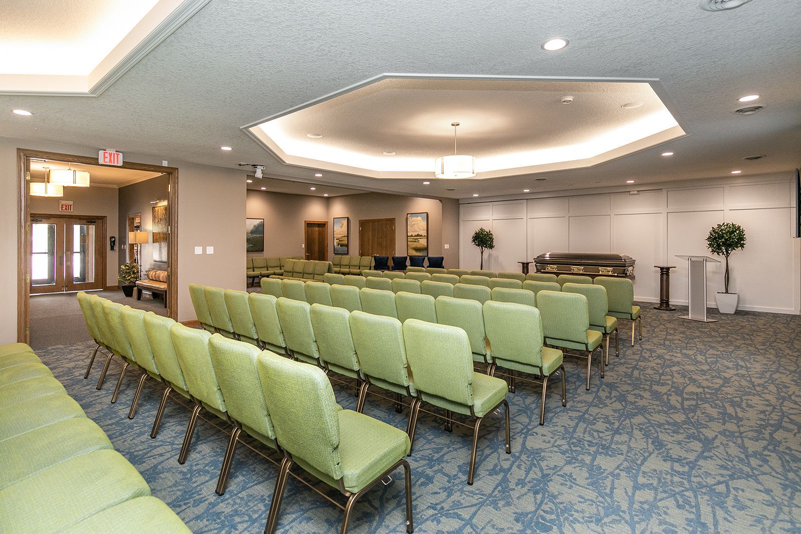 A large room with rows of green chairs in it