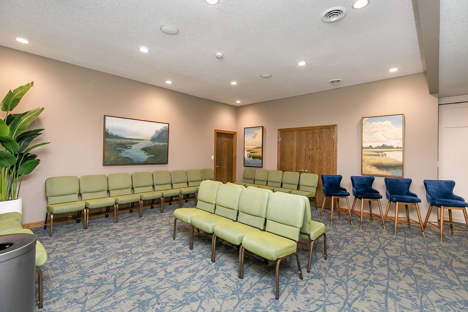 A waiting room with a lot of chairs and a painting on the wall.
