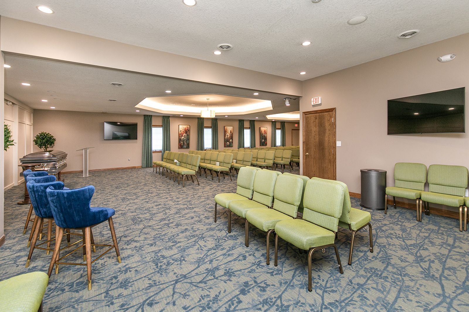 A large waiting room with green chairs and blue chairs.