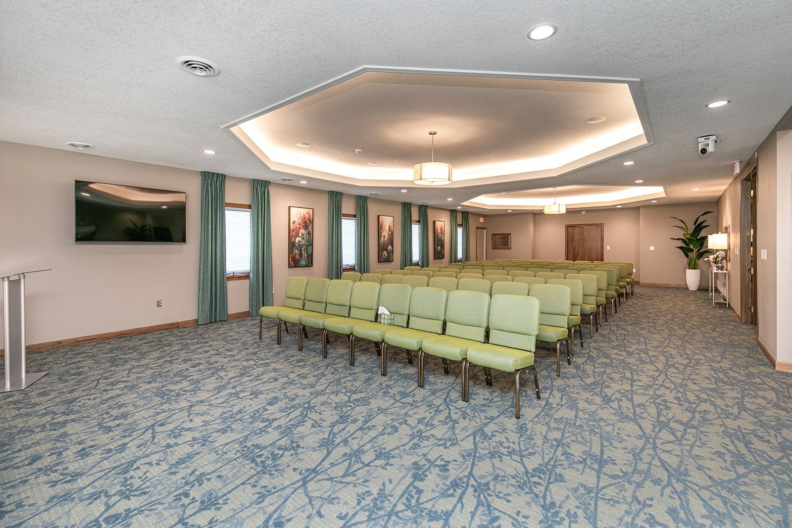 A large room with rows of chairs and a television on the wall.