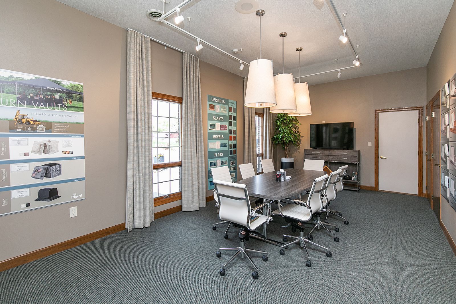 A conference room with a table and chairs and a television.