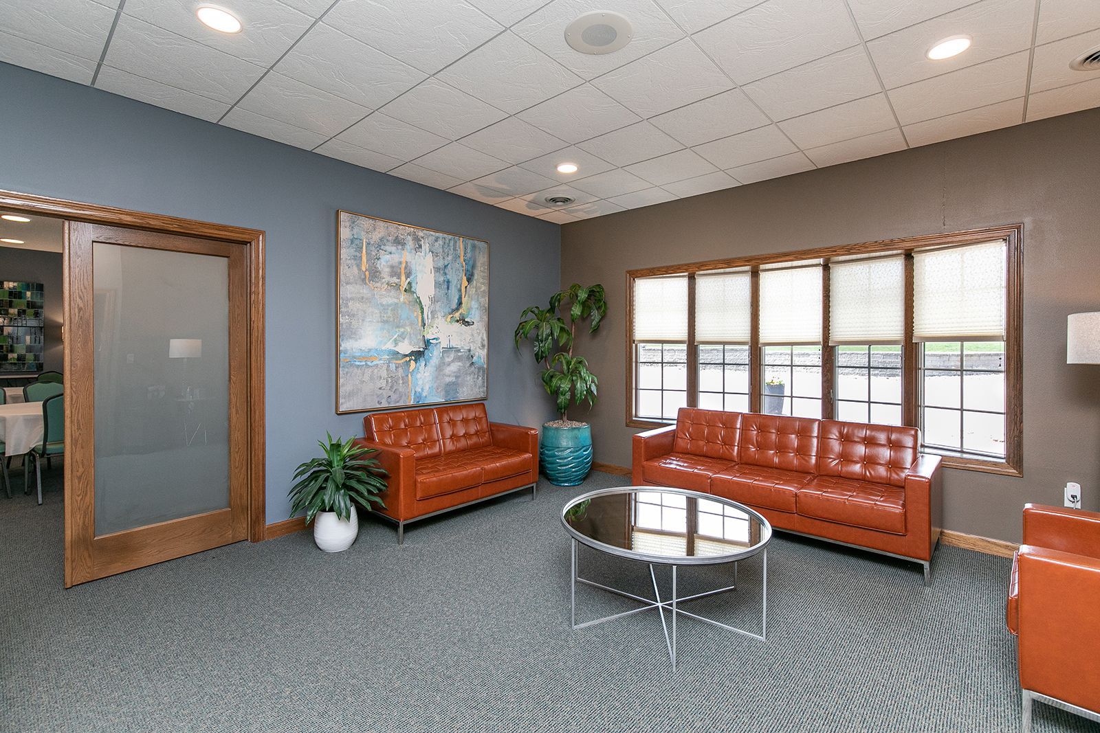 A living room with a couch , chair , coffee table and refrigerator.
