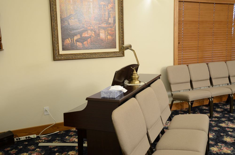 A room with a piano and chairs and a picture on the wall