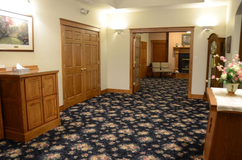 A hallway with a floral carpet and a clock on the wall