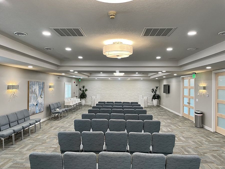 A large room with rows of chairs and a chandelier.