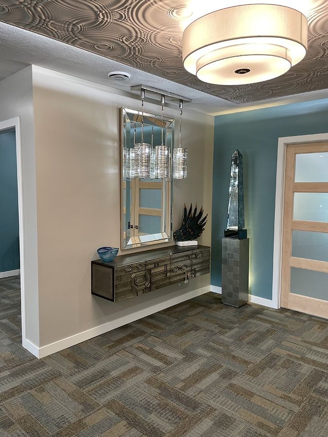 A hallway with a mirror on the wall and a ceiling light.