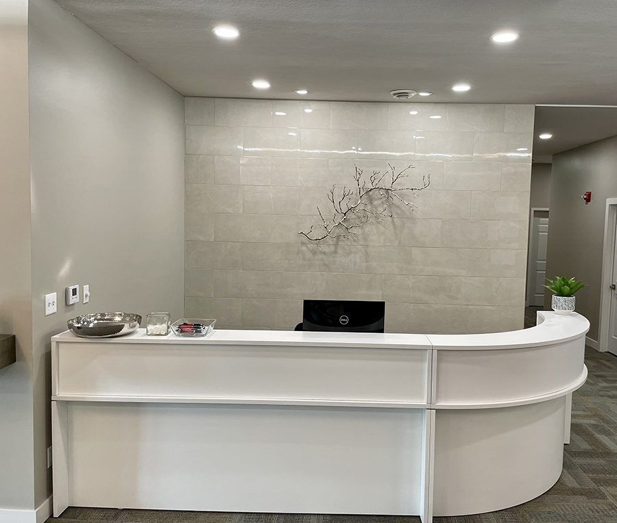 A white reception desk in a dental office with a computer on it.