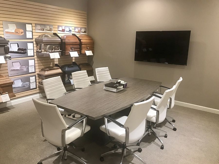 A conference room with a table and chairs and a flat screen tv.