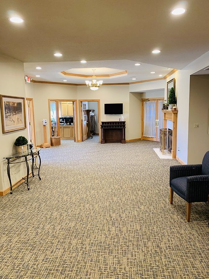 A large room with a chair , table , television and fireplace.