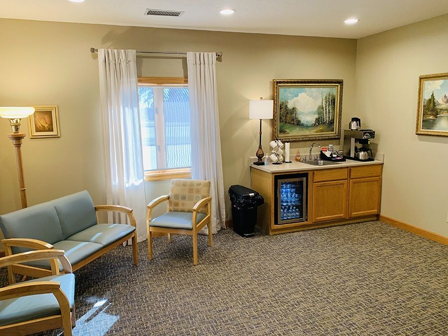 A waiting room with a couch , chairs , and a coffee bar.