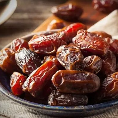 Een mand met rijpe, donkerrode kersen met groene steeltjes.