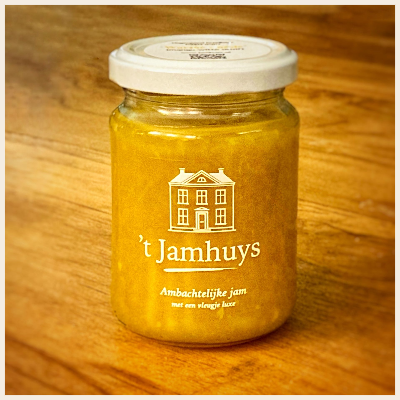 Pot gele jam houten ondergrond. Op het etiket staat een tekening van een huis en de tekst