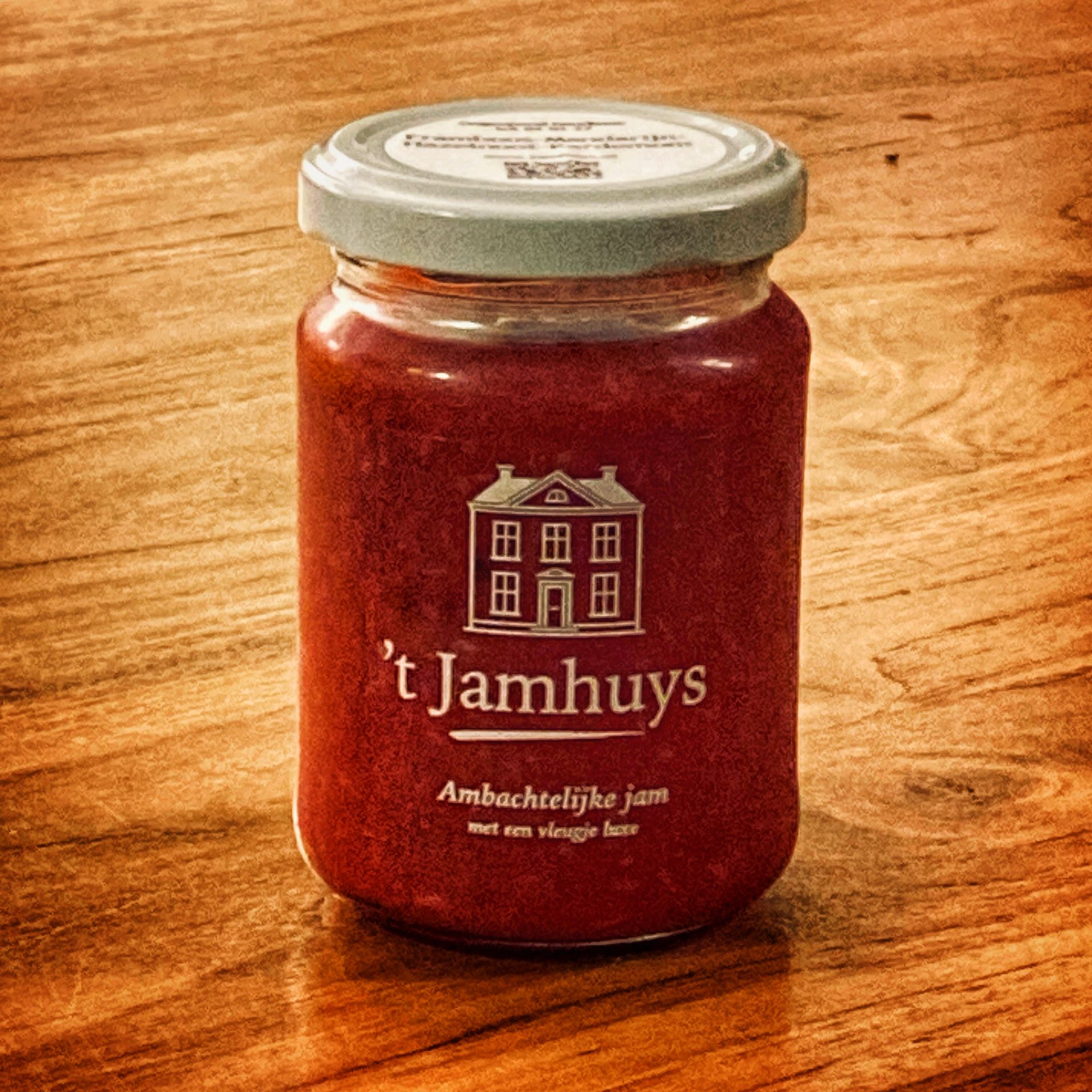 Pot rode jam op een houten ondergrond, met wit etiket waarop 