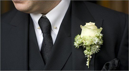 A man in a black suit with a white rose