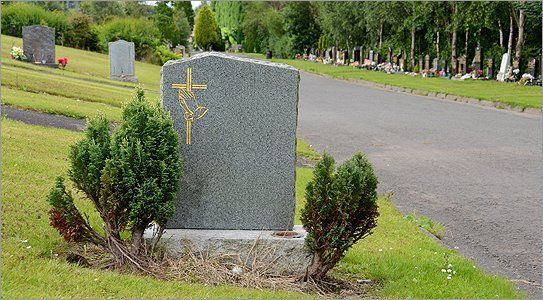 A headstone with an engraving of a cross and prayer hands