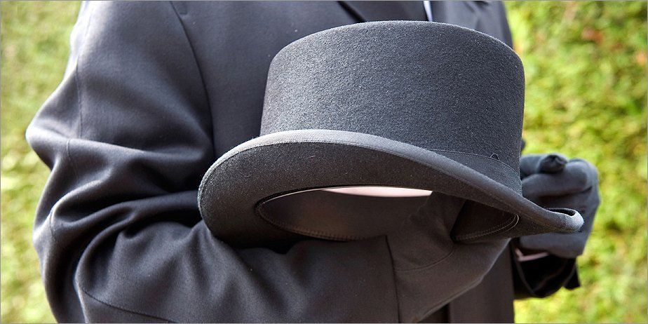 A funeral director holding a top hat