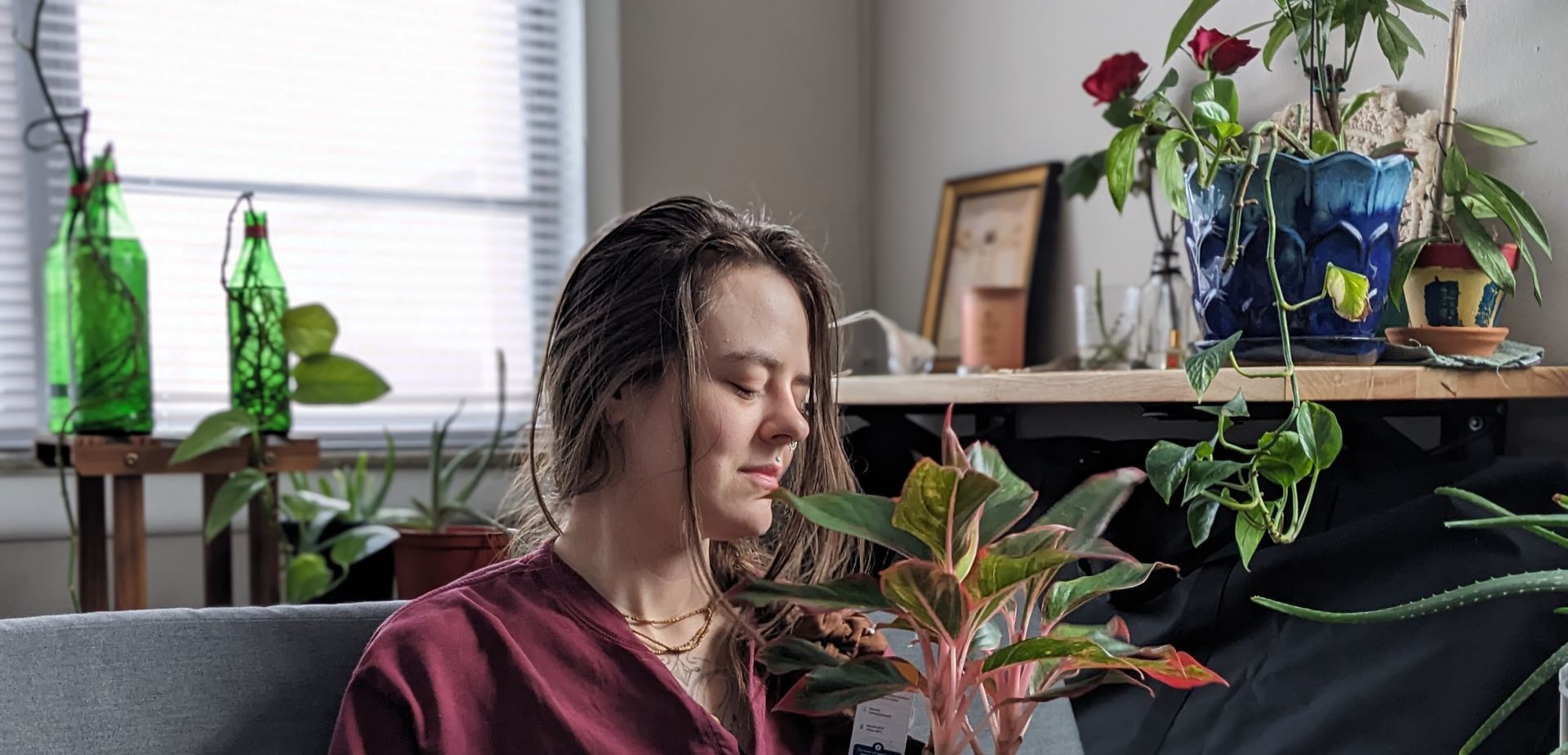 A woman is sitting on a couch holding a potted plant.