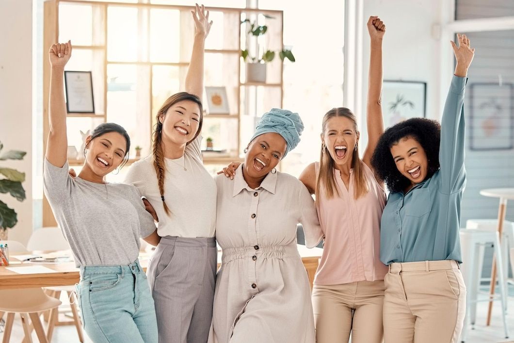A group of women are standing next to each other with their arms in the air.