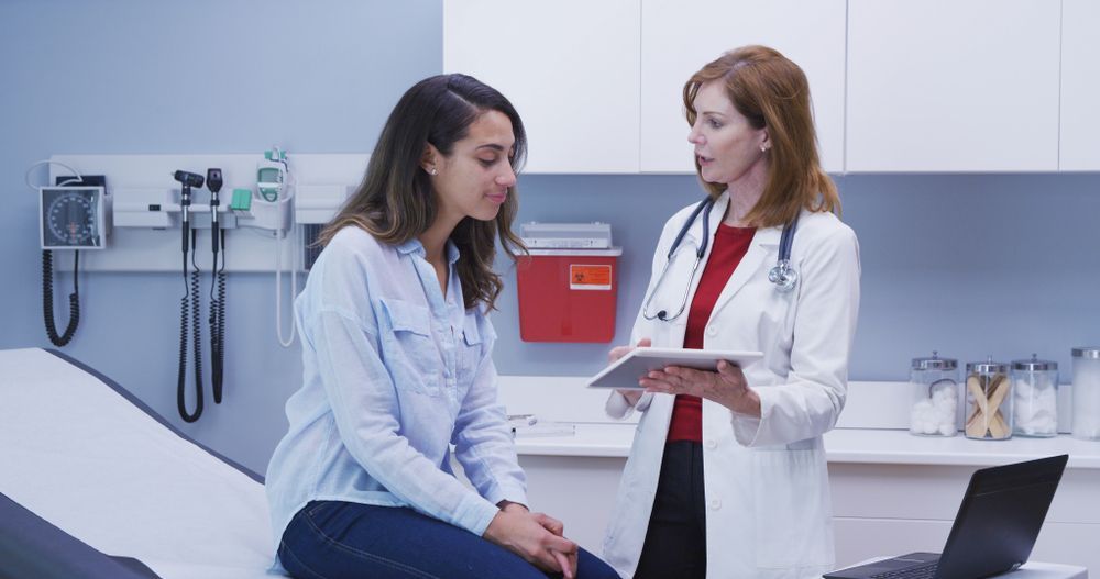 A doctor is talking to a patient who is sitting on a bed in a hospital.