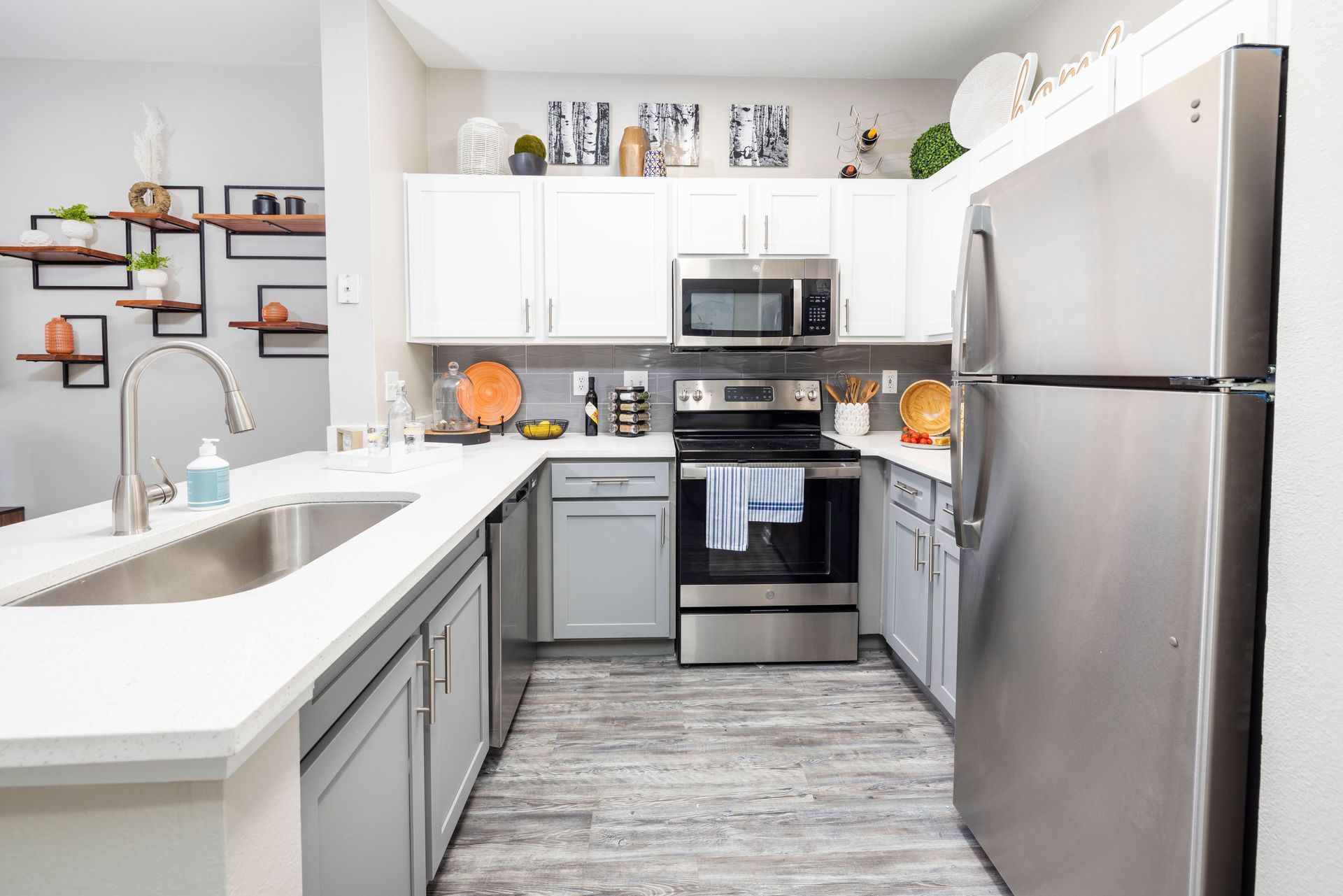A kitchen with stainless steel appliances , white cabinets , a sink , and a refrigerator.