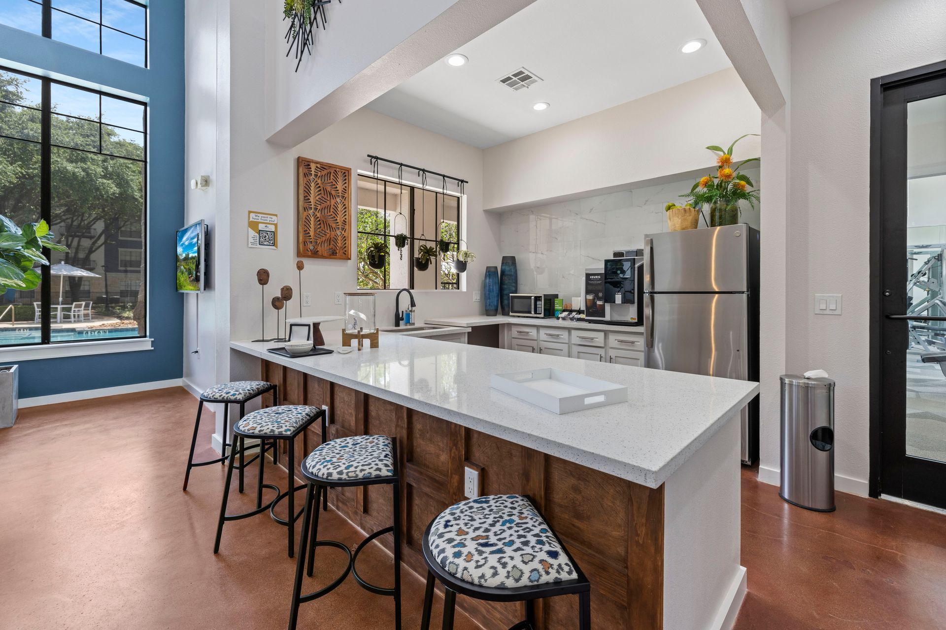 A kitchen with a large island , stools and a refrigerator.